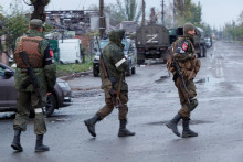 Príslušníci proruských jednotiek prechádzajú cez cestu pred odchodom ukrajinských vojakov, ktorí sa vzdali v obliehanej oceliarni Azovstaľ. FOTO: Reuters
