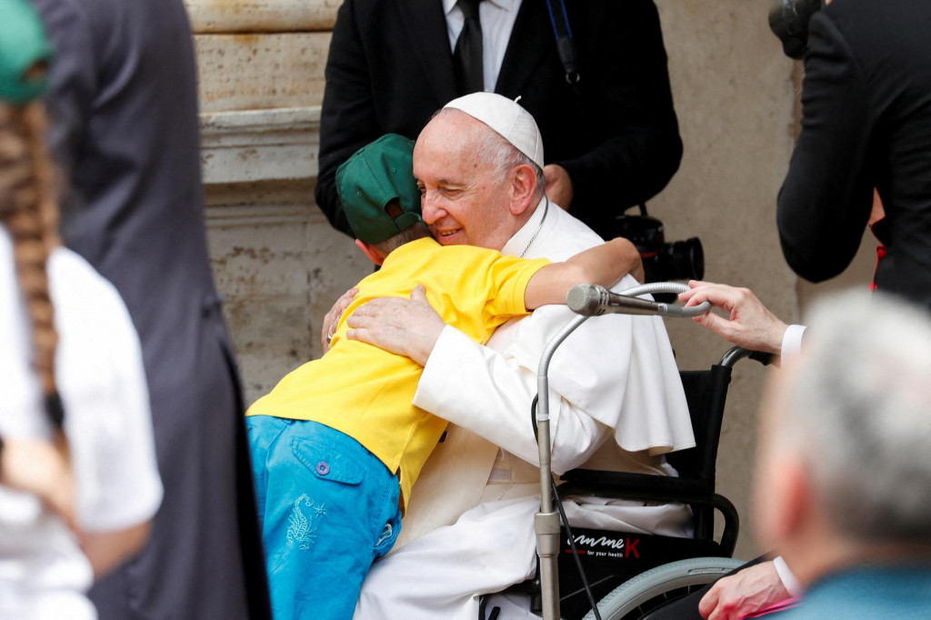 Pápež František objíma dieťa počas stretnutia s deťmi so zdravotným postihnutím a ukrajinskými deťmi. FOTO: Reuters