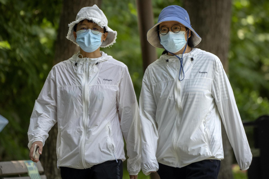 Ženy s ochrannými rúškami kráčajú vo verejnom parku v čínskom Pekingu 2. júna 2022. FOTO: TASR/AP