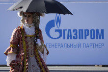 Herec v kostýme znázorňujúcom odev z 18. storočia prechádza okolo loga ruskej spoločnosti Gazprom v Petrohrade. FOTO: Dmitri Lovetsky