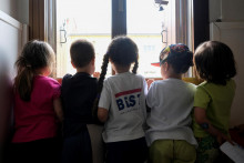 Deti stoja pri okne v škôlke.  FOTO: Reuters