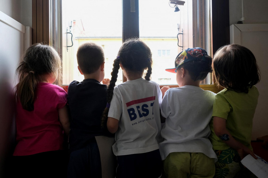 Deti stoja pri okne v škôlke.  FOTO: Reuters
