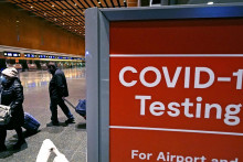 Na archívnej snímke z 21. decembra 2021 cestujúci prechádzajú okolo nápisu testovacie miesto na ochorenie COVID-19 na termináli E letiska Logan v Bostone. FOTO: TASR/AP

