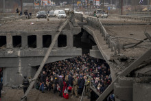 Na archívnej snímke z 5. marca 2022 ľudia, ktorí utekajú počas vojny zo svojich domovov, sa zhromaždili pod zničeným mostom pri rieke Irpiň na predmestí Kyjeva. FOTO: TASR/AP

