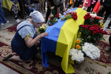 Žena kľačí pri rakve s pozostatkami Romana Ratušného. FOTO: TASR/AP