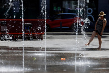 Žena sa hrá vo fontáne počas slnečného počasia v Bruseli. FOTO: Reuters 