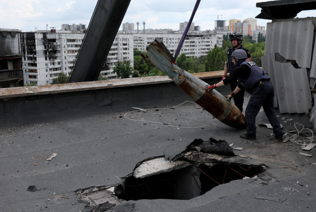 Členovia špecializovaného tímu odstraňujú zneškodnenú bombu, ktorá nevybuchla, v Charkove. FOTO: Reuters 