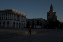 Žena kráča pri západe slnka po Námestí nezávislosti v centre Kyjeva. FOTO: Reuters