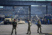 &lt;p&gt;Ukrajinskí vojaci stoja pred budovou nákupného centra po ruskom raketovom útoku v ukrajinskom meste Kremenčuk. FOTO: TASR/AP&lt;/p&gt;