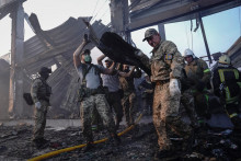 Záchranári pracujú na mieste nákupného centra zasiahnutého ruským raketovým útokom v Kremenčuku. FOTO: Reuters