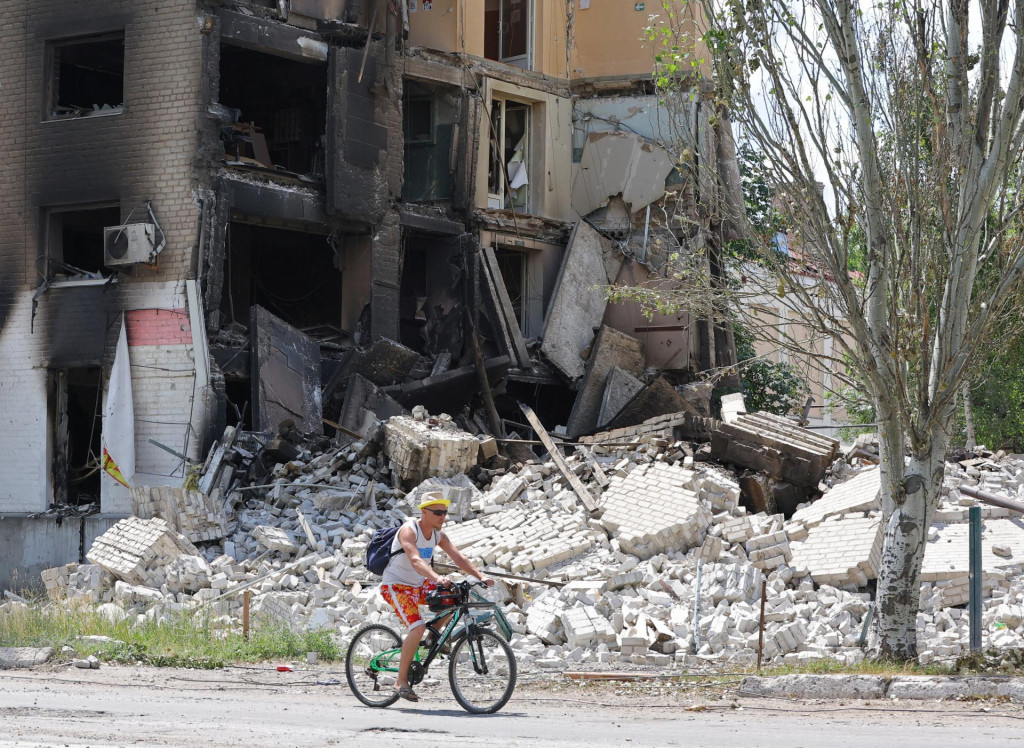 Miestny obyvateľ jazdí na bicykli popri budove zničenej počas ukrajinsko-ruského konfliktu v meste Lysyčansk. FOTO: Reuters 