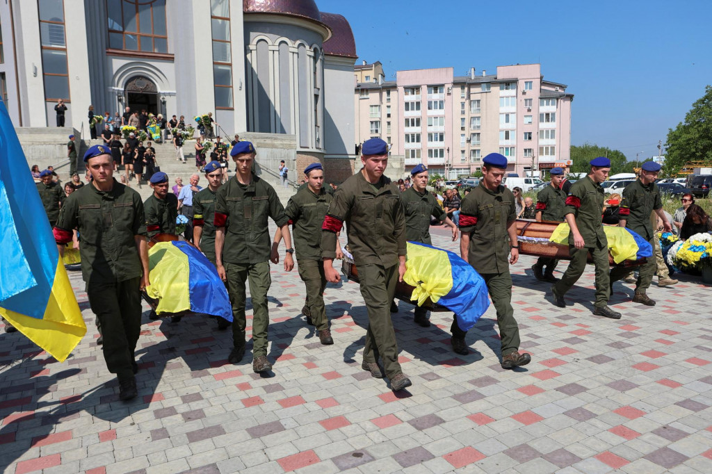 Pr&iacute;slu&scaron;n&iacute;ci N&aacute;rodnej gardy nes&uacute; rakvy pr&iacute;slu&scaron;n&iacute;kov ukrajinskej arm&aacute;dy. FOTO: REUTERS