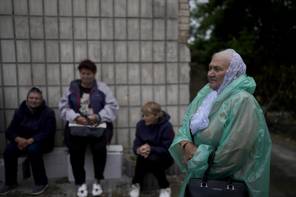 Žena čaká v rade na sociálnu pomoc v Makarive v Kyjevskej oblasti. FOTO: TASR/AP
 