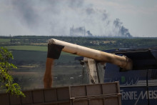 Farmers harvest wheat as Vuhlehirsk&#39;s heat power plant burns in the distance after a shelling, amid Russia&#39;s attack on Ukraine, in the Donbas region, Ukraine July 13, 2022. REUTERS/Gleb Garanich SNÍMKA: Gleb Garanich