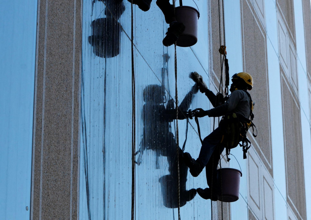 Pracovníci umývajú okná výškovej budovy. FOTO: Reuters