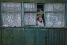 Obyvateľka Ukrajiny stojí za oknom a pozerá na následky ruského ostreľovania. FOTO: REUTERS