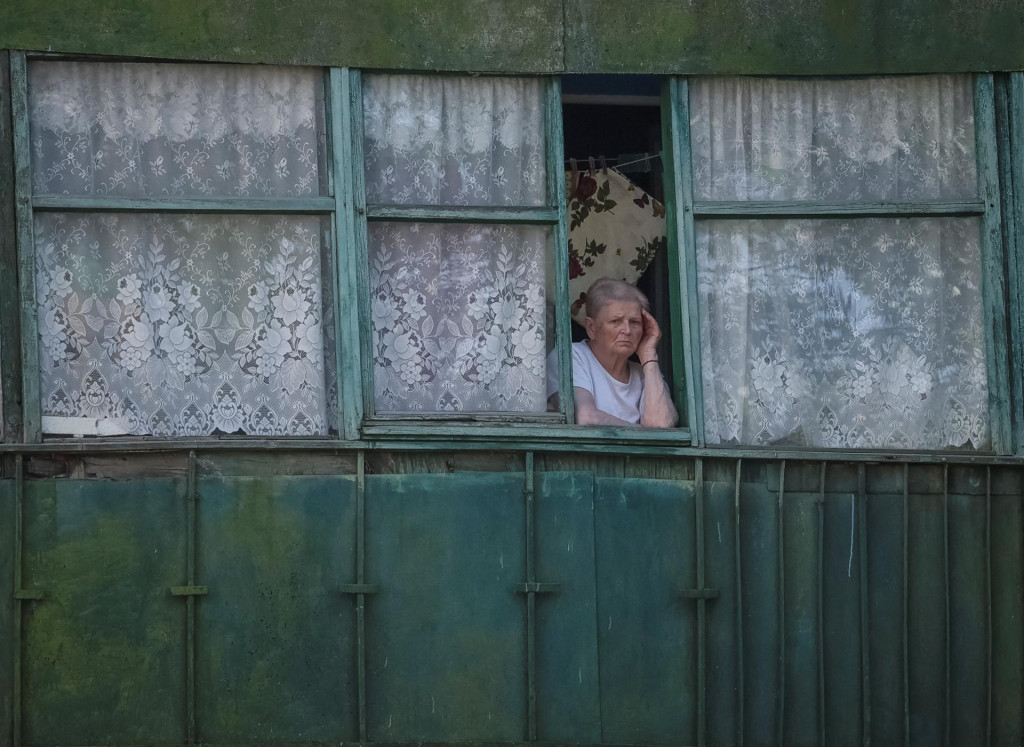 Obyvateľka Ukrajiny stojí za oknom a pozerá na následky ruského ostreľovania. FOTO: REUTERS