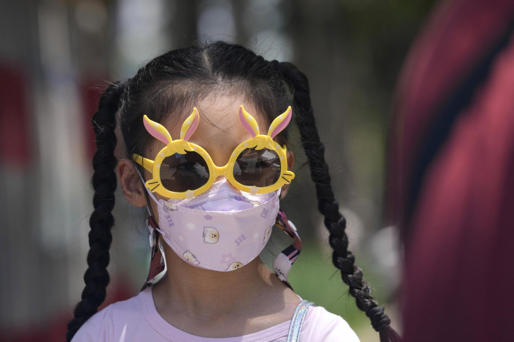 Dievča s ochranným rúškom a so slnečnými okuliarmi. FOTO: TASR/AP
