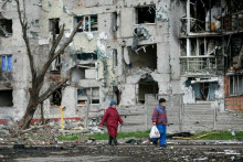 Ľudia v blízkosti obytnej budovy v meste Mariupol na Ukrajine. FOTO: Reuters