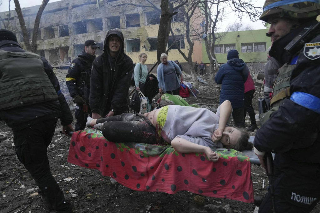 Ukrajinskí záchranári a dobrovoľníci nesú zranenú tehotnú ženu po ostreľovaní pôrodnice v Mariupole počas štrnásteho dňa ruskej invázie na Ukrajine v stredu 9. marca 2022. Ruská armáda pri vtedajšom ostreľovaní Mariupolu zasiahla a zničila detskú nemocnicu a pôrodnicu, tvrdia miestni činitelia aj ukrajinský prezident Volodymyr Zelenskyj. FOTO: REUTERS