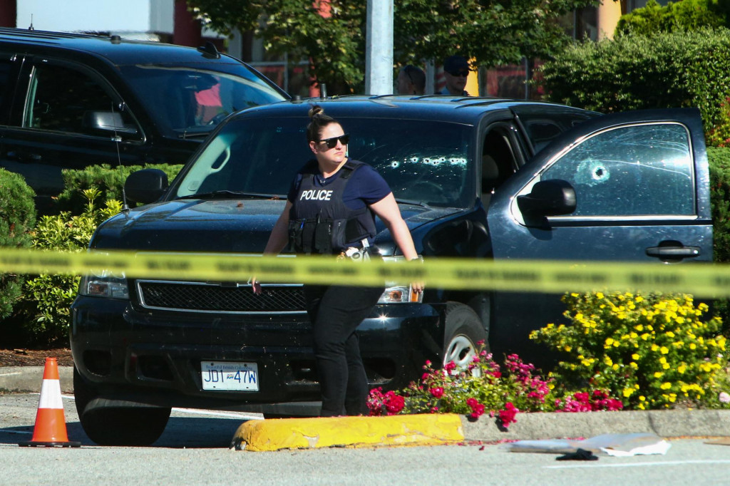 Policajt kráča vedľa auta s dierami po guľkách na oknách na mieste činu po tom, čo úrady upozornili obyvateľov na niekoľkonásobnú streľbu na predmestí Vancouveru v Langley, Britská Kolumbia, Kanada 25. júla 2022. FOTO: REUTERS