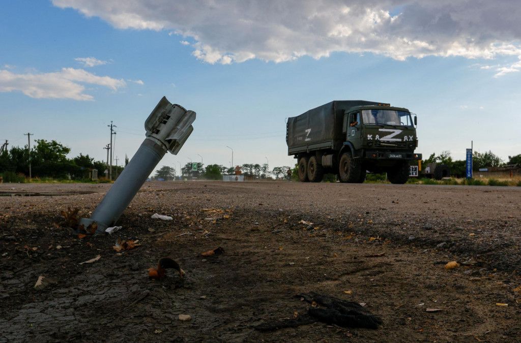 Ruské vojenské nákladné auto prechádza okolo nevybuchnutej munície. FOTO: Reuters