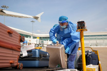 Pracovník v ochrannom obleku prepravuje batožinu v priestoroch medzinárodného letiska Wu-chan. FOTO: Reuters