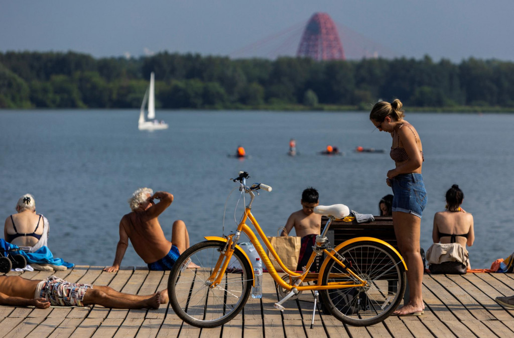 Ľudia odpočívajú pri rieke Moskva počas horúceho počasia. FOTO: Reuters