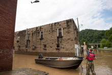 Muž signalizuje helikoptére Národnej gardy letiacej nad hlavou po dni silného dažďa v Garrette v Kentucky. FOTO: Reuters