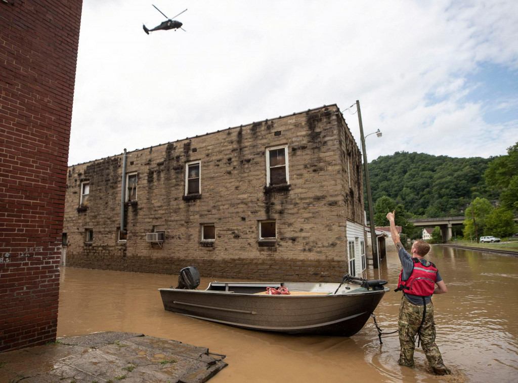 Muž signalizuje helikoptére Národnej gardy letiacej nad hlavou po dni silného dažďa v Garrette v Kentucky. FOTO: Reuters