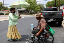 Žena rozdáva vodu a klobúky počas vĺn horúčav v San Antoniu v Texase. FOTO: Reuters