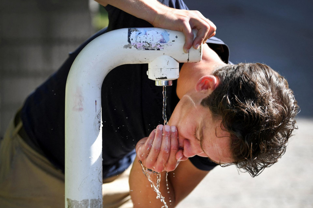 Muž pije vodu z verejného pitia počas horúčav v holandskom Nijmegene. FOTO: Reuters