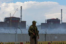 Mechanik s ruskou vlajkou na uniforme stojí na stráži pri Záporožskej jadrovej elektrárni. FOTO: Reuters
