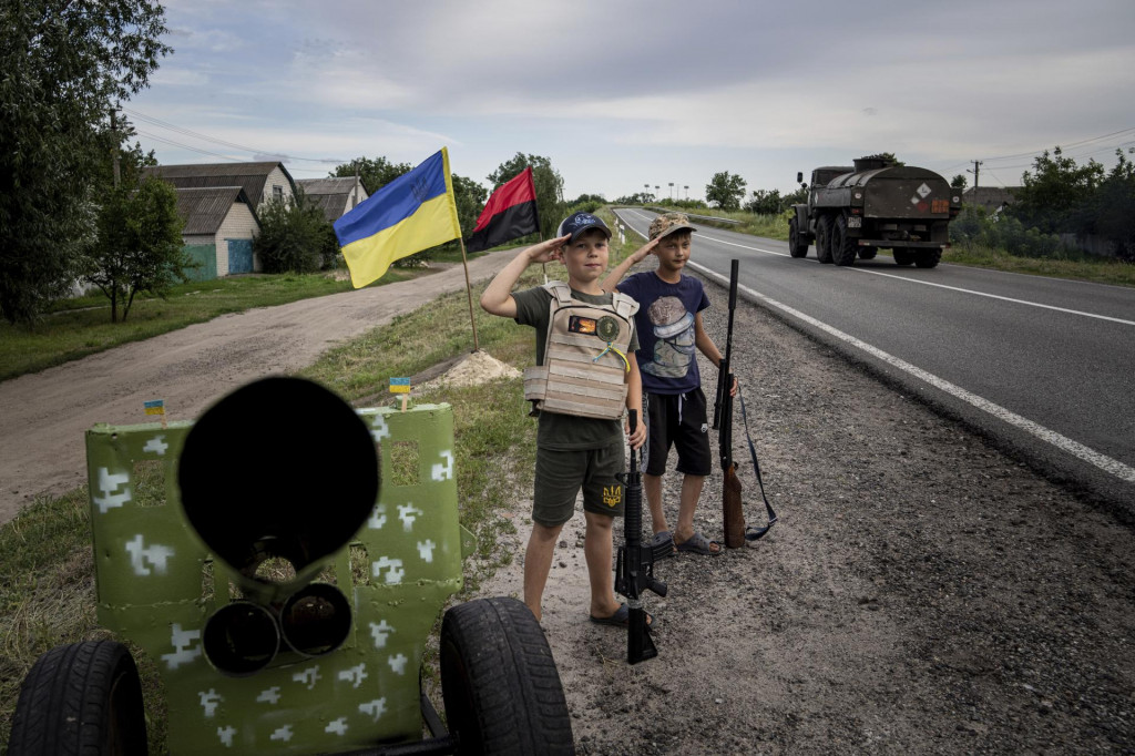Dvaja jedenásťroční chlapci zdravia ukrajinských vojakov na diaľnici v Charkovskej oblasti. FOTO: TASR/AP

