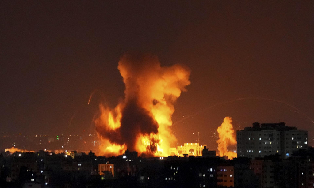 Dym a plamene stúpajú z budovy zasiahnutej raketami vystrelenými palestínskymi militantmi na Izrael v Gaze. FOTO: TASR/AP