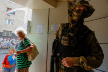 Príslušník proruských jednotiek pred úradom, keď sa miestni obyvatelia zhromažďujú, aby predložili dokumenty a získali ruské občianstvo a pas v okupovanom meste Cherson na Ukrajine 25. júla 2022. FOTO: REUTERS