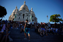 Turisti sedia pred bazilikou Sacre-Coeur na Butte Montmartre v Paríži. FOTO: Reuters