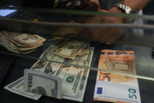 Zamestnanec zamieňa bankovku v hodnote 50 eur na americké doláre v zmenárni v Ríme. FOTO: TASR/AP