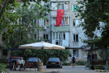 Vlajky Sovietskeho zväzu a Ruska vyvesené na obytnej budove v okupovanom prístavnom meste Mariupol na Ukrajine 16. júla 2022. FOTO: REUTERS