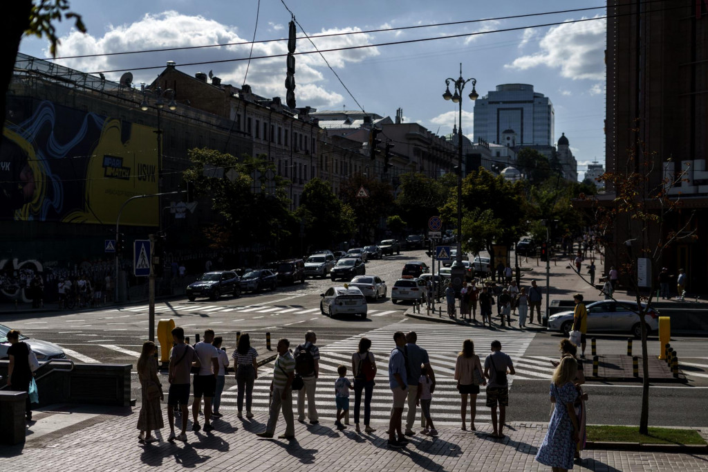 Ľudia stoja na križovatke pred priechodom pre chodcov v Kyjeve. FOTO: TASR/AP