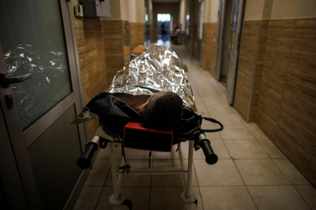 Zranený ukrajinský vojak leží na nosidlách na chodbe vojenskej nemocnice. FOTO: Reuters