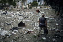 Žena kráča okolo budovy zničenej pri nočnom bombardovaní. FOTO: TASR/AP