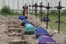 Kňaz sa modlí za neidentifikovaných civilistov zavraždených ruskými jednotkami počas ruskej okupácie v ukrajinskej Buči. FOTO: TASR/AP