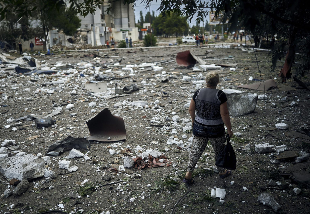 Žena kráča okolo budovy zničenej pri nočnom bombardovaní. FOTO: TASR/AP