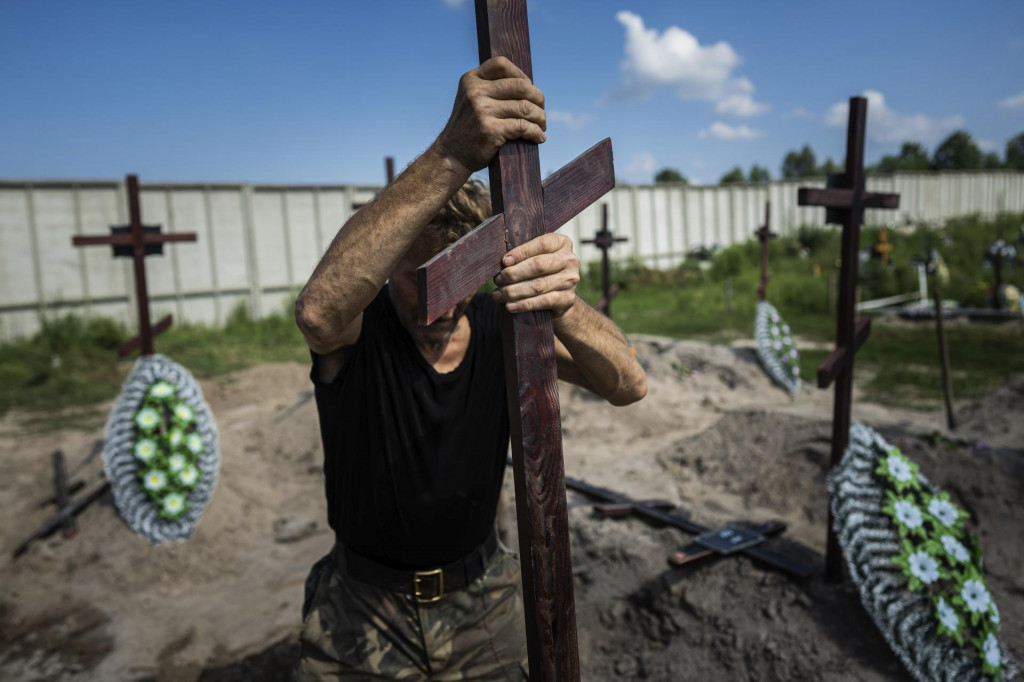 Pracovník pohrebnej služby dáva kríž s číslom na hrob neidentifikovaného civilistu, ktorého zabili príslušníci ruskej armády. FOTO: TASR/AP
