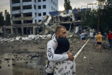 Muž a žena sa objímajú pred budovou zničenou pri ruskom nočnom bombardovaní v Mykolajive na juhu Ukrajiny 3. augusta 2022. Podľa miestnych médií bol zničený supermarket, výškové budovy a lekáreň. FOTO: TASR/AP