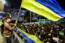 Muž máva vlajkou z balkóna pred demonštrantmi, ktorí sa zúčastňujú na zhromaždení na podporu Ukrajiny. FOTO: REUTERS