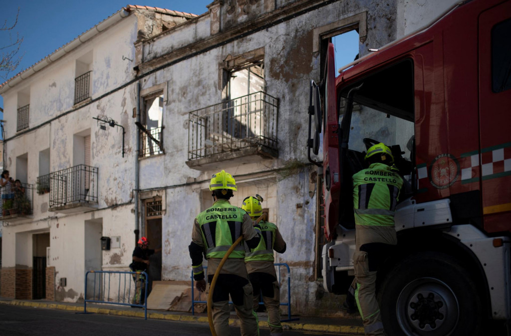 Hasiči stoja pred vyhoreným domom v regióne Valencia. FOTO: Reuters