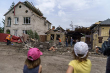 Deti sledujú ako ľudia upratujú po raketovom útoku na dom v Kramatorsku v Doneckej oblasti. FOTO: TASR/AP