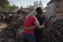 Ukrajinské ženy sa objímajú pred budovou zničenou pri raketovom útoku v Charkove. FOTO: TASR/AP